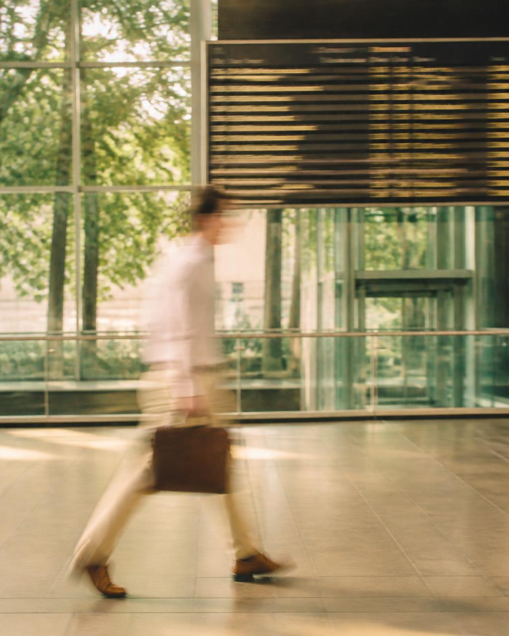 Business traveller in motion blur walking through a modern European station lobby in summer