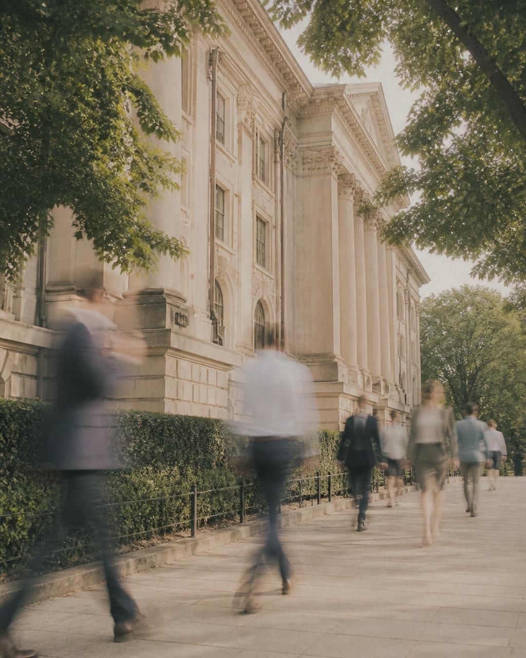 Pedestrians in motion blur outside a neoclassical government building in summer